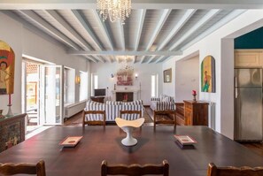 Comedor con una larga mesa de madera, sillas acolchadas, un candelabro y una chimenea.