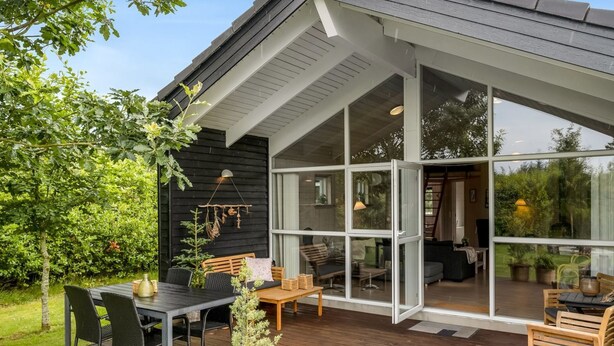 Une maison moderne dotée d’une terrasse, de grandes baies vitrées et d’un jardin.