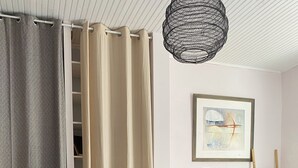 Ett modernt sovrum med en säng, kuddar, en hängande lampa, en tavla och en stege som står lutad mot väggen.