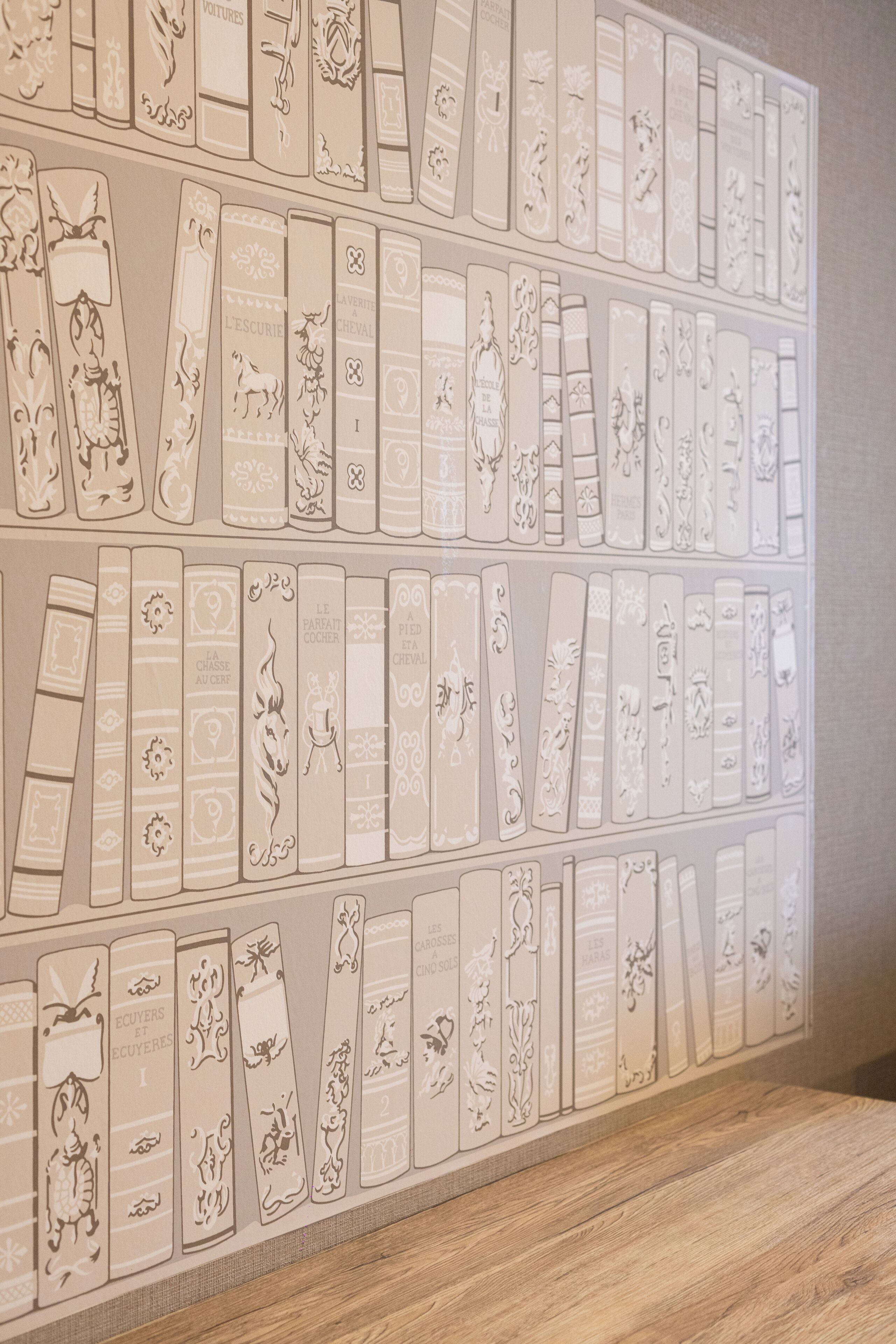 A wall with embossed book spines, each spine featuring unique designs and text.
