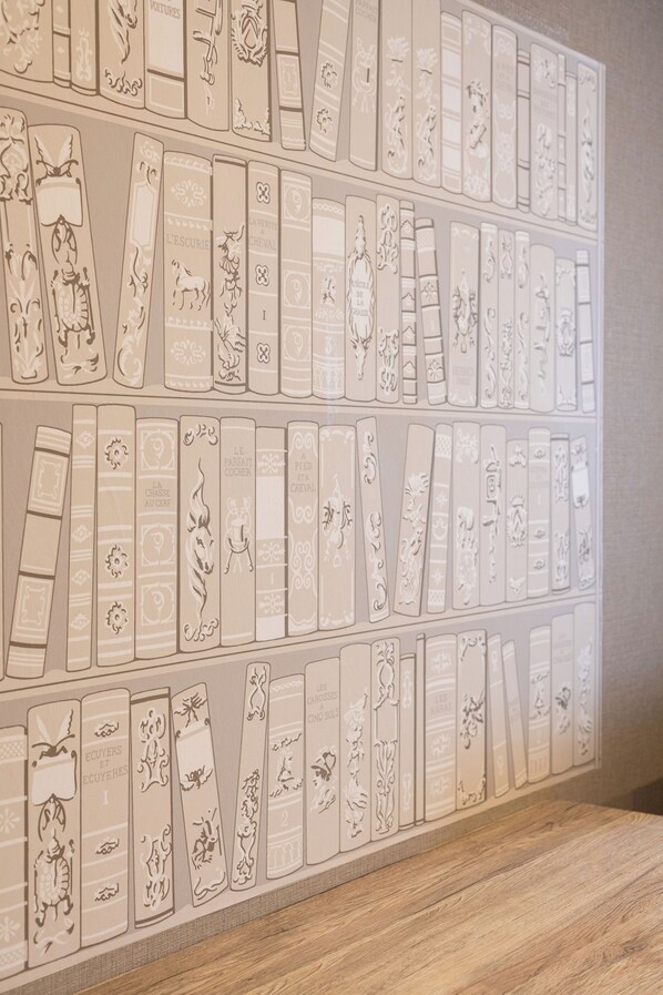 Un mur orné de motifs en relief représentant des dos de livres, chaque dos présentant des motifs et des textes uniques.