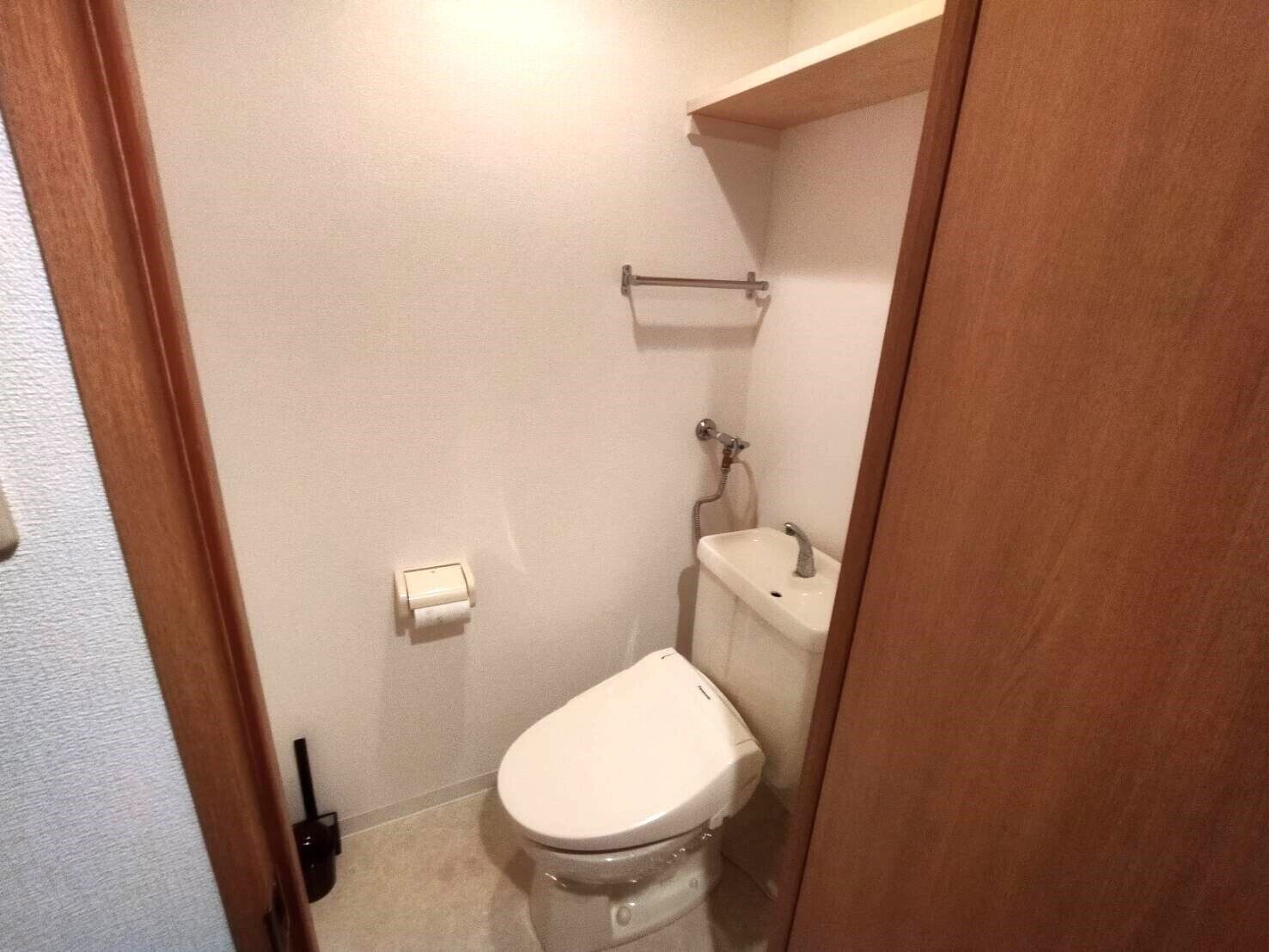 Une petite salle de bain compacte, équipée de toilettes, d’un lavabo et d’un porte-serviettes.