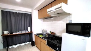 Μια μικρή, λειτουργική κουζίνα με εστίες, φούρνο μικροκυμάτων και νεροχύτη.