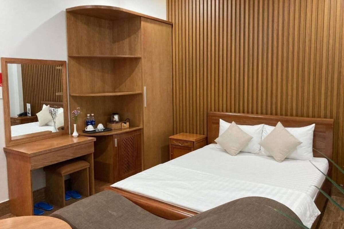 Una habitación de hotel con una cama de madera, un escritorio con espejo y un armario.
