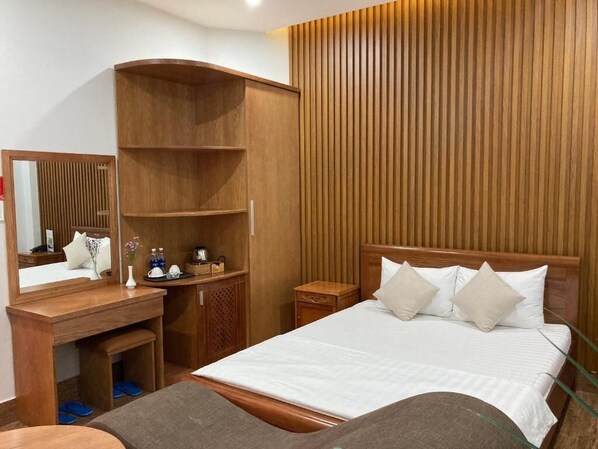 Ein Hotelzimmer mit einem hölzernen Bett, einem Schreibtisch mit Spiegel und einem Kleiderschrank.