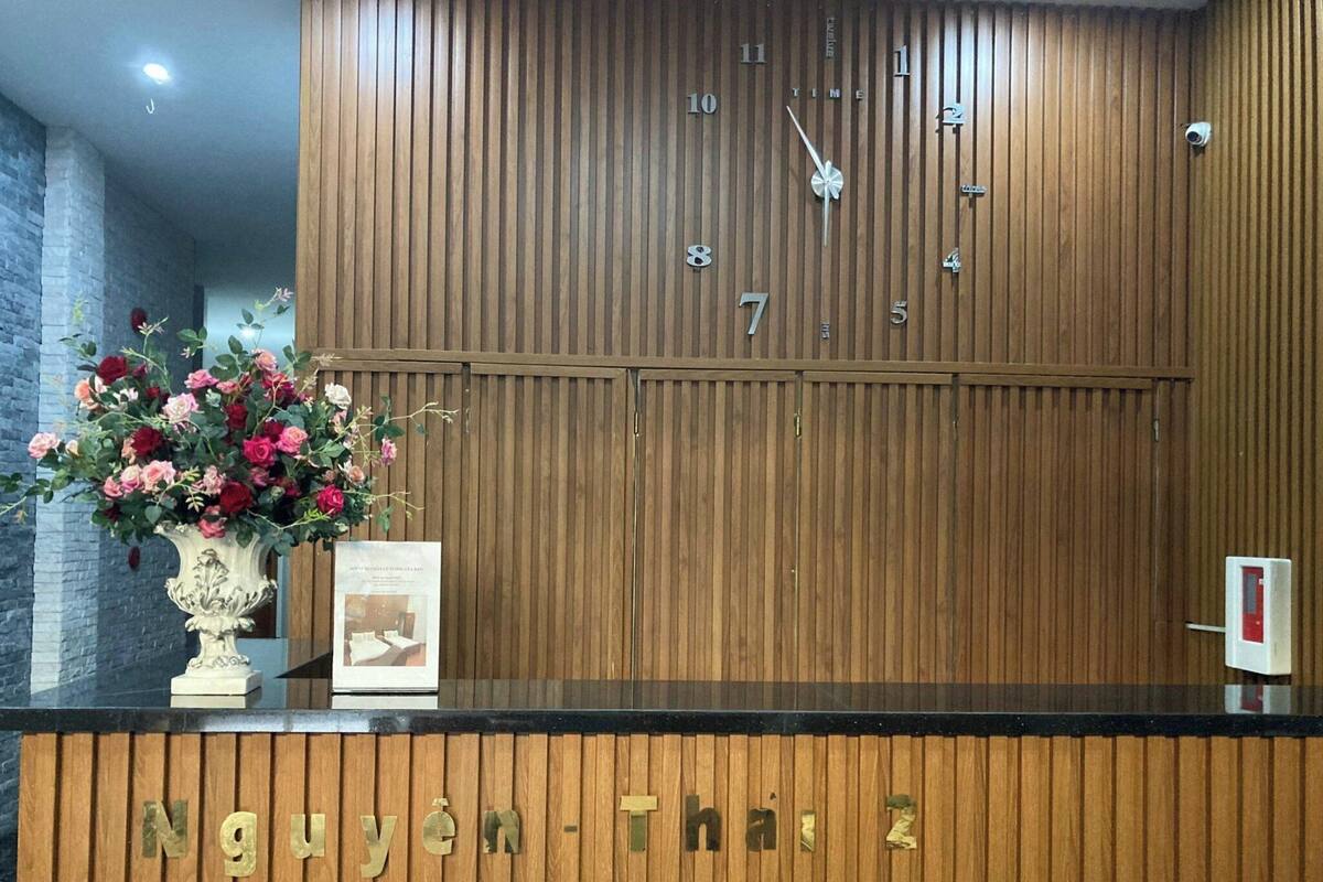Un mostrador de recepción con paneles de madera, un reloj y un arreglo floral.