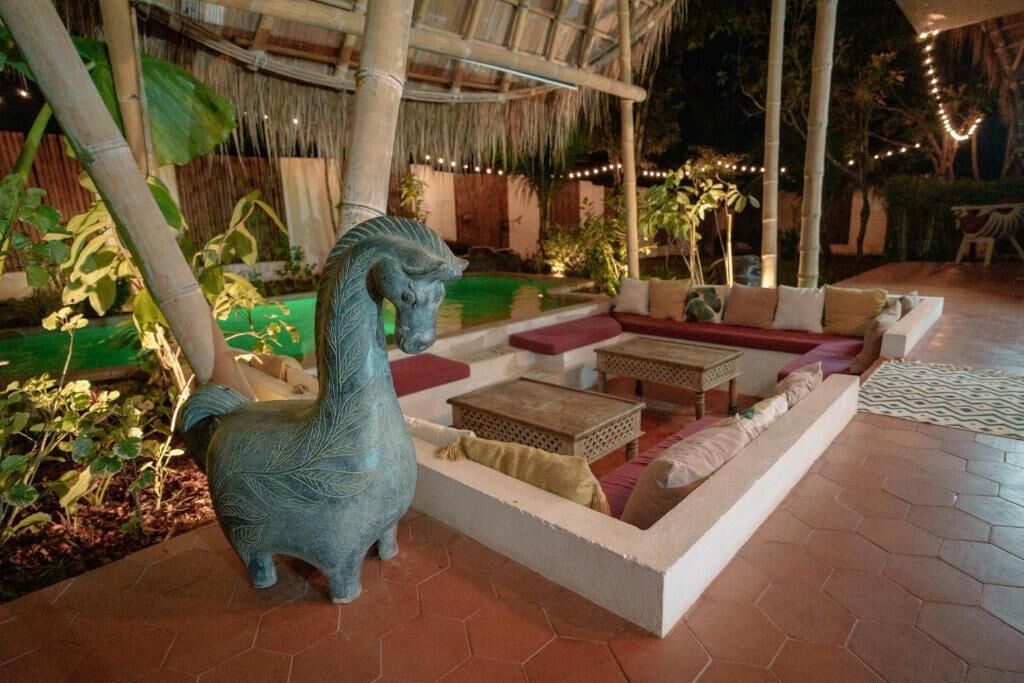 A courtyard with a stone bench, a decorative horse sculpture, and a pool.