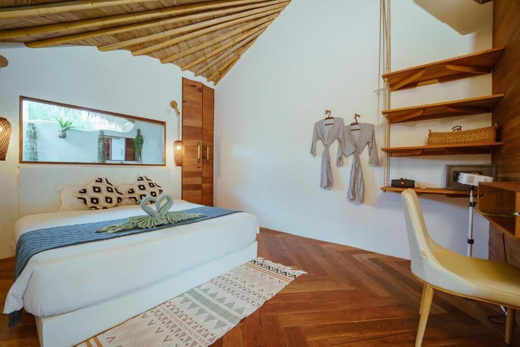 Een slaapkamer met een bed, houten plafond, een spiegel en een kledingkast.