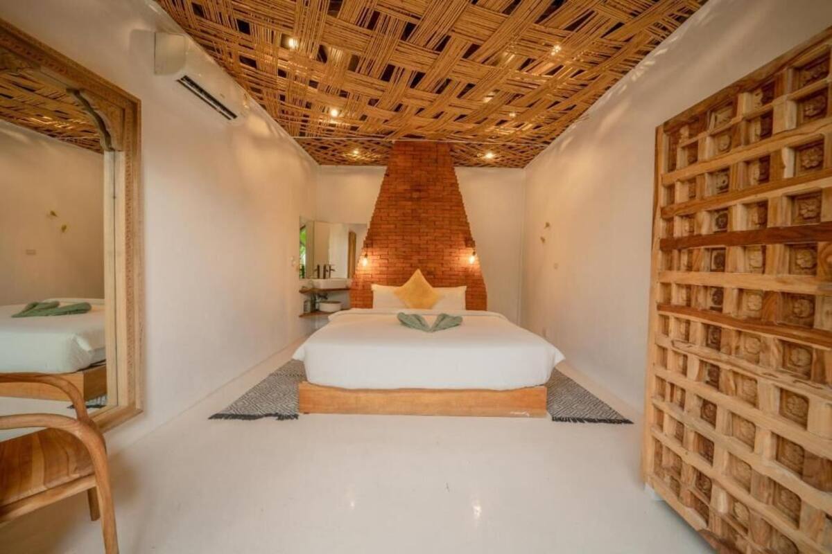 A bedroom with a large bed, a wooden ceiling, and a wall of wooden blocks.