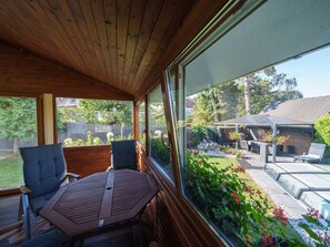 A covered patio with wooden flooring, a table, and two chairs.