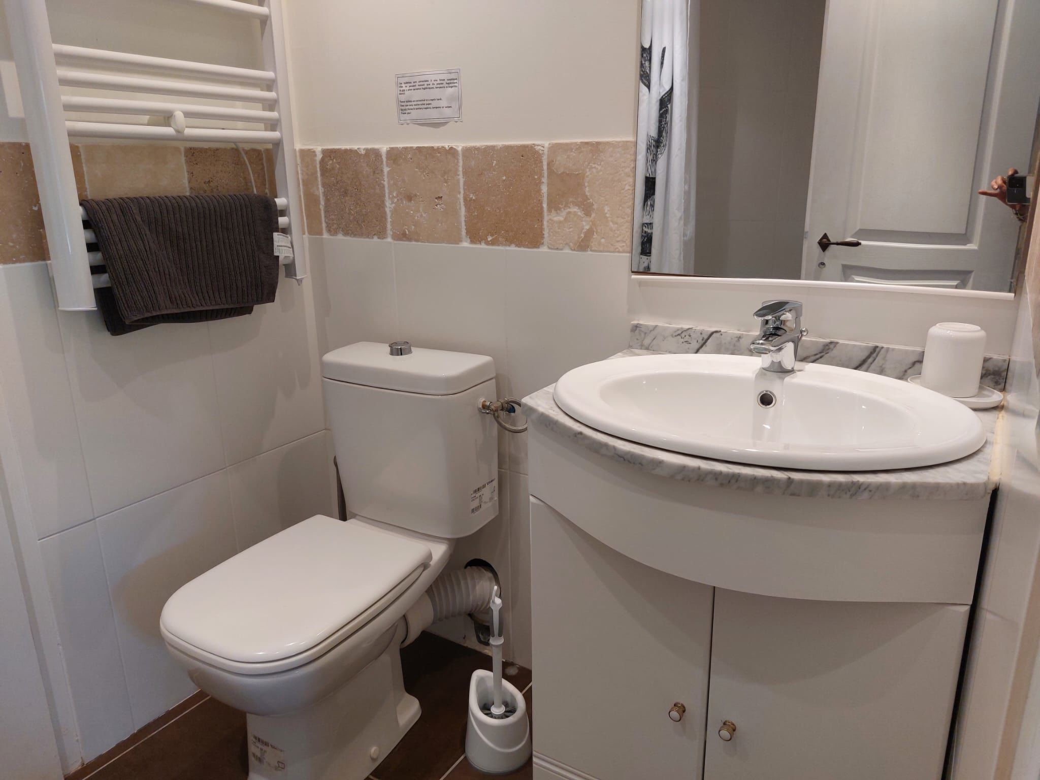 Un baño con inodoro, lavabo y toallero.
