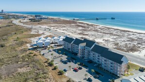 Vue aérienne d’un hôtel situé sur la côte, composé de plusieurs bâtiments, d’un parking et d’une plage.