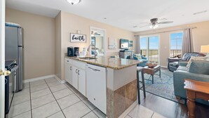 Une cuisine moderne avec un îlot central, un coin repas doté d’un canapé bleu et un balcon avec vue.