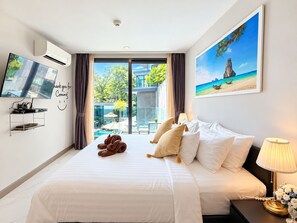 Habitación de hotel con cama, televisión, un cuadro y vistas a una piscina y vegetación.