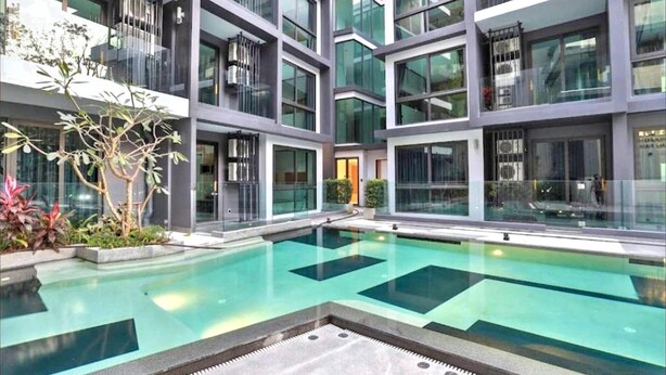 Ein modernes Gebäude mit Pool, großen Fenstern und einem Balkon.