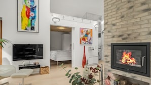 Una sala de estar moderna con chimenea, televisor y obras de arte en las paredes.