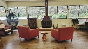 Una sala de estar con dos sillones rojos, una mesa de centro de madera y una chimenea grande.