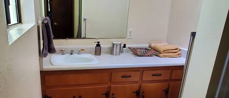 A compact bathroom with a white sink, wooden cabinets, a toilet, and a mirror above the sink.