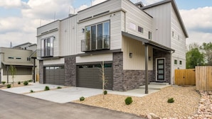 Une maison moderne à deux étages, dotée d’un garage, d’un balcon et d’un jardin bien entretenu.
