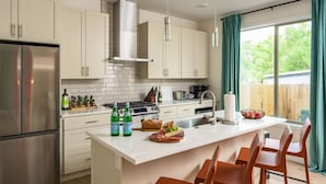 Une cuisine moderne avec des armoires blanches, des appareils en acier inoxydable et un îlot central doté de sièges.
