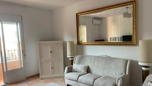 A living room with a sofa, a table, a cabinet, and a large mirror. - The Beautiful Views II (Noalejo)
