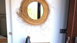 A wooden console table with drawers against a white door, topped with a circular mirror and a small decorative item. - Atenea House (Caldes de Malavella)