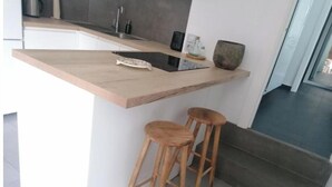 A kitchen with a wooden countertop, two wooden stools, a fish decoration, and a modern sink. - Atenea House (Caldes de Malavella)