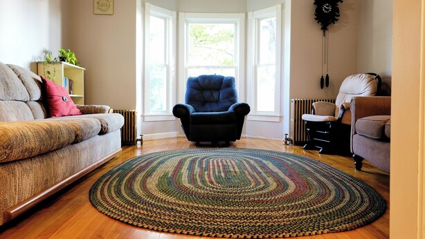 A living room with a blue armchair, a beige armchair, a patterned rug, and a bookshelf with books and a plant. - Pretty Old House in Newport (Newport)