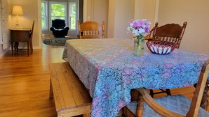 A dining area with a wooden table and chairs, a vase with flowers, and a chandelier. - Pretty Old House in Newport (Newport)