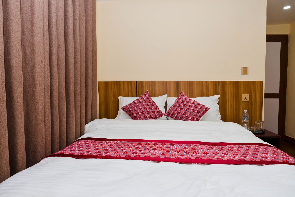 Een hotelkamer met een groot bed, een houten hoofdbord en een rood-witte bedspreide.