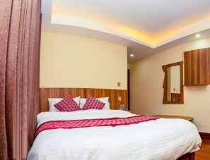 Una habitación de hotel con una cama grande, cabecero de madera y un espejo en la pared.