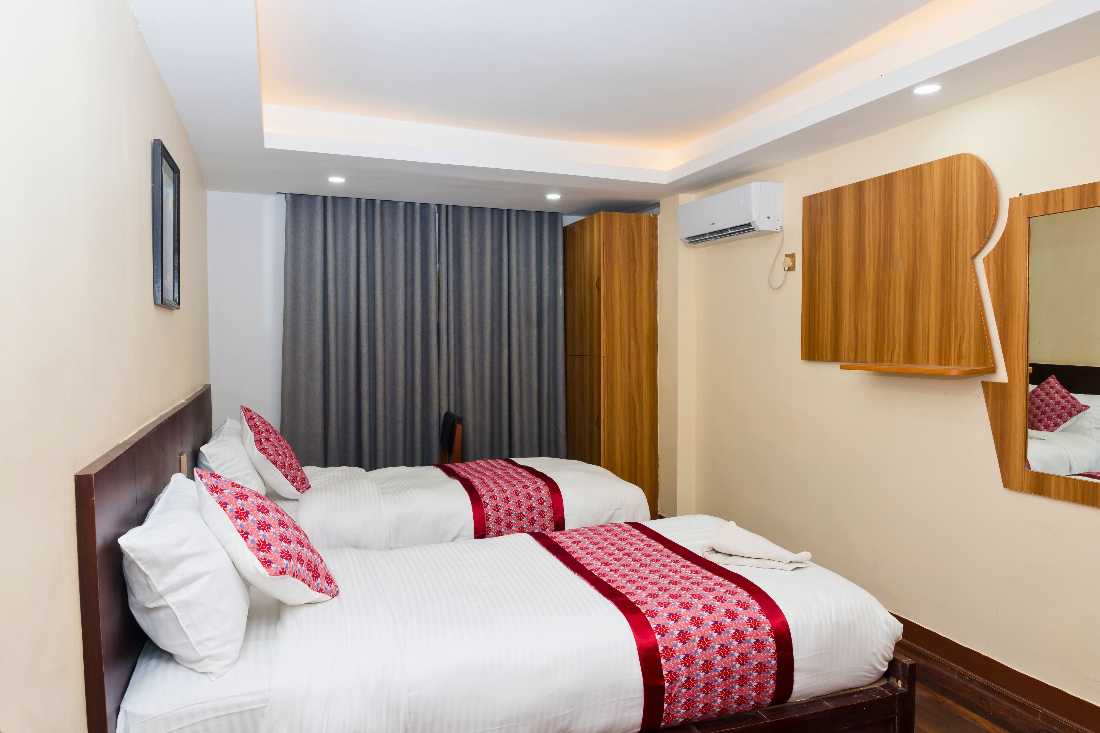 A hotel room with two beds, a wooden headboard, a mirror, and a window with curtains.