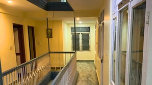 A corridor with a marble floor, a staircase with a metal railing, and a window with blinds. - Rightway Hotel & Restaurant (Kathmandu)