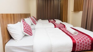 A hotel room with a large bed, multiple pillows, and a red and white patterned bedspread. - Rightway Hotel & Restaurant (Kathmandu)