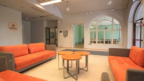 Un interior moderno con sofás naranja, una mesa de madera y un amplio ventanal de arco.