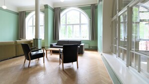Una habitación amplia con un gran ventanal de arco, un sofá, dos sillas y una mesa de centro de madera.