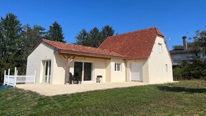 A single-story house with a red-tiled roof, a covered patio, and a white fence.