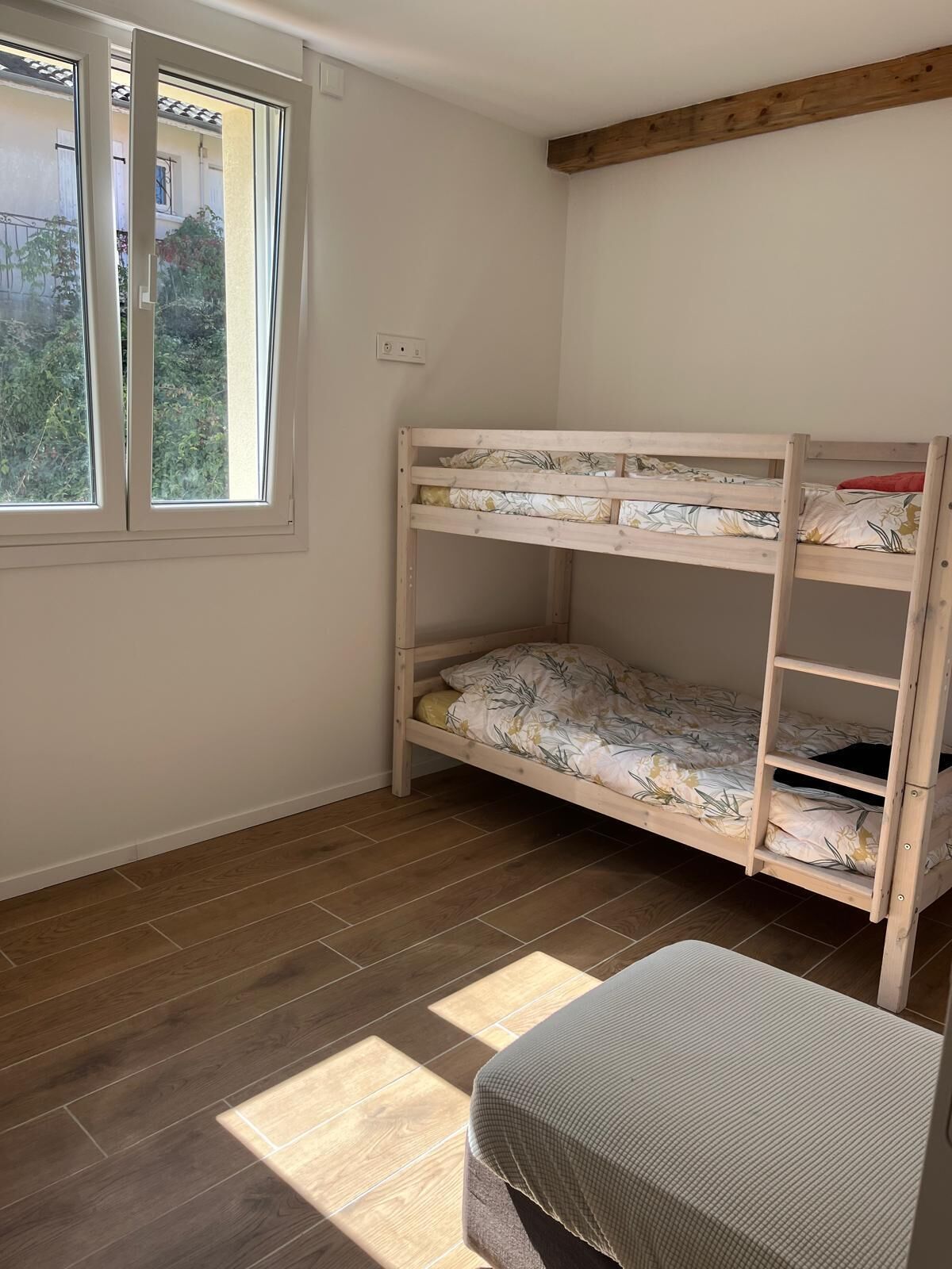 A room with a bunk bed, a window, and a small table.