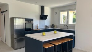 A modern kitchen with a central island, stainless steel appliances, and a window providing natural light.