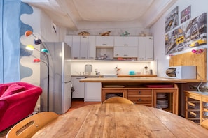 A compact kitchen with white cabinets, a wooden dining table, and a microwave. - Agde Heritage, No. 16 (Agde)