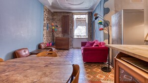 Une pièce avec une table en bois, des chaises, un canapé rouge, un ventilateur de plafond et un sol à motifs.