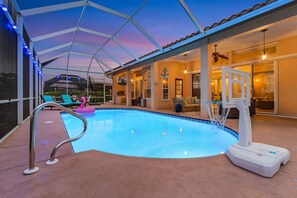 A swimming pool with a diving board and lounge chairs under a covered patio. - Gorgeous, Gulf Access canal, Heated Pool, Kayaks, Bicycles - Villa Mango - Roelens (Cape Coral)