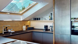 A modern kitchen with a skylight, built-in appliances, and a large island.