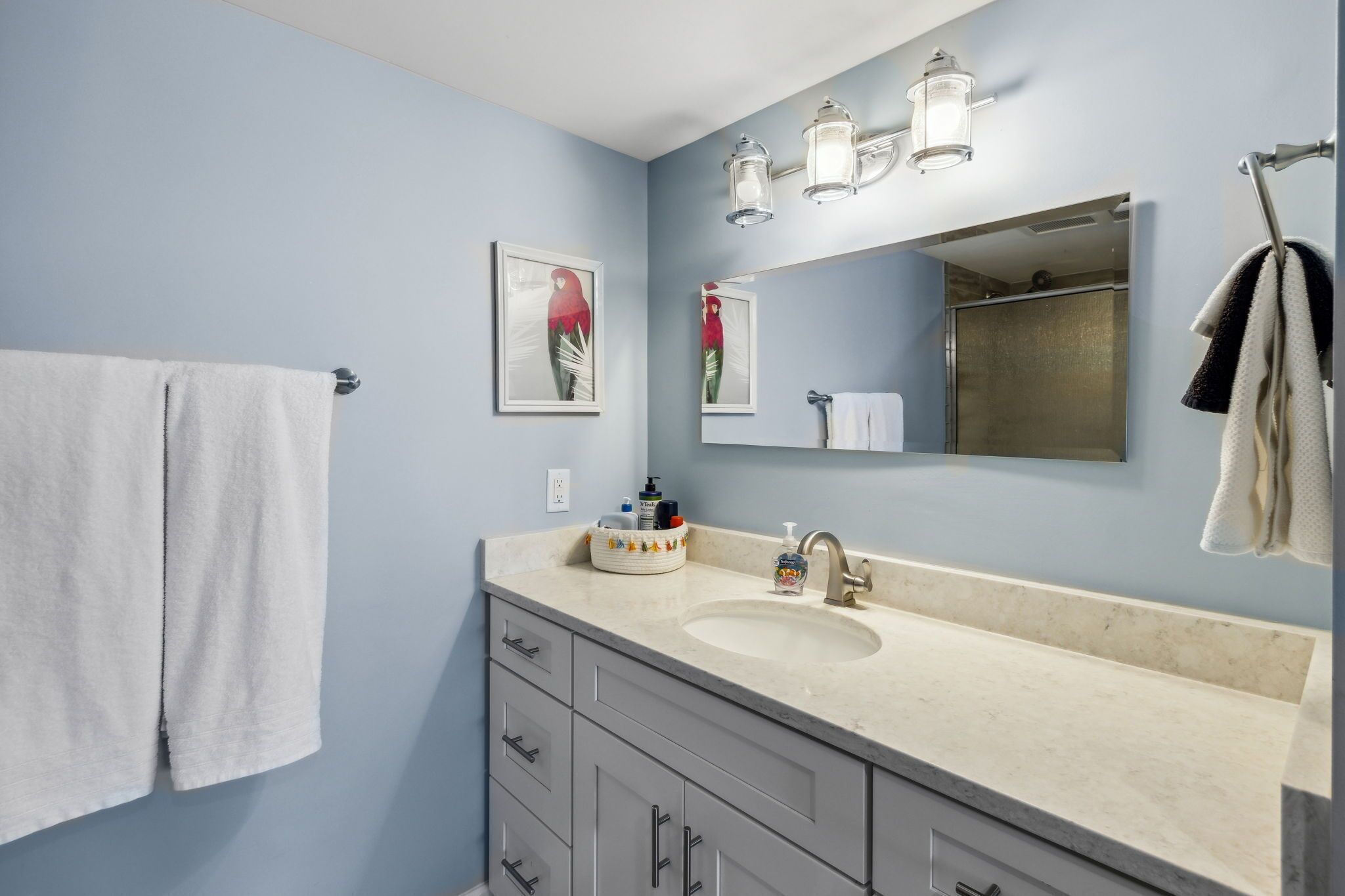 A bathroom with a sink, mirror, and towel rack.