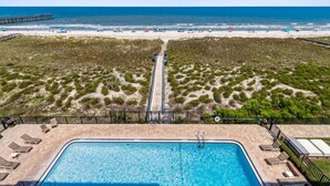 A pool with a view of the beach and a pier. - Oceanfront 3BR condo with pool, balcony, and beach access. (Fernandina Beach)