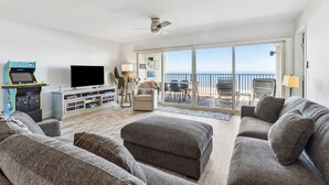 A living room with a flat-screen TV, a gaming console, and a sofa. - Oceanfront 3BR condo with pool, balcony, and beach access. (Fernandina Beach)