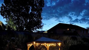 A gazebo with string lights, surrounded by gravel and a concrete path. - 5 BR Charming Home Near Temple/SUU with Game Room (Cedar City)