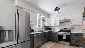 Una cocina moderna con electrodomésticos de acero inoxidable, armarios blancos y suelo de madera.