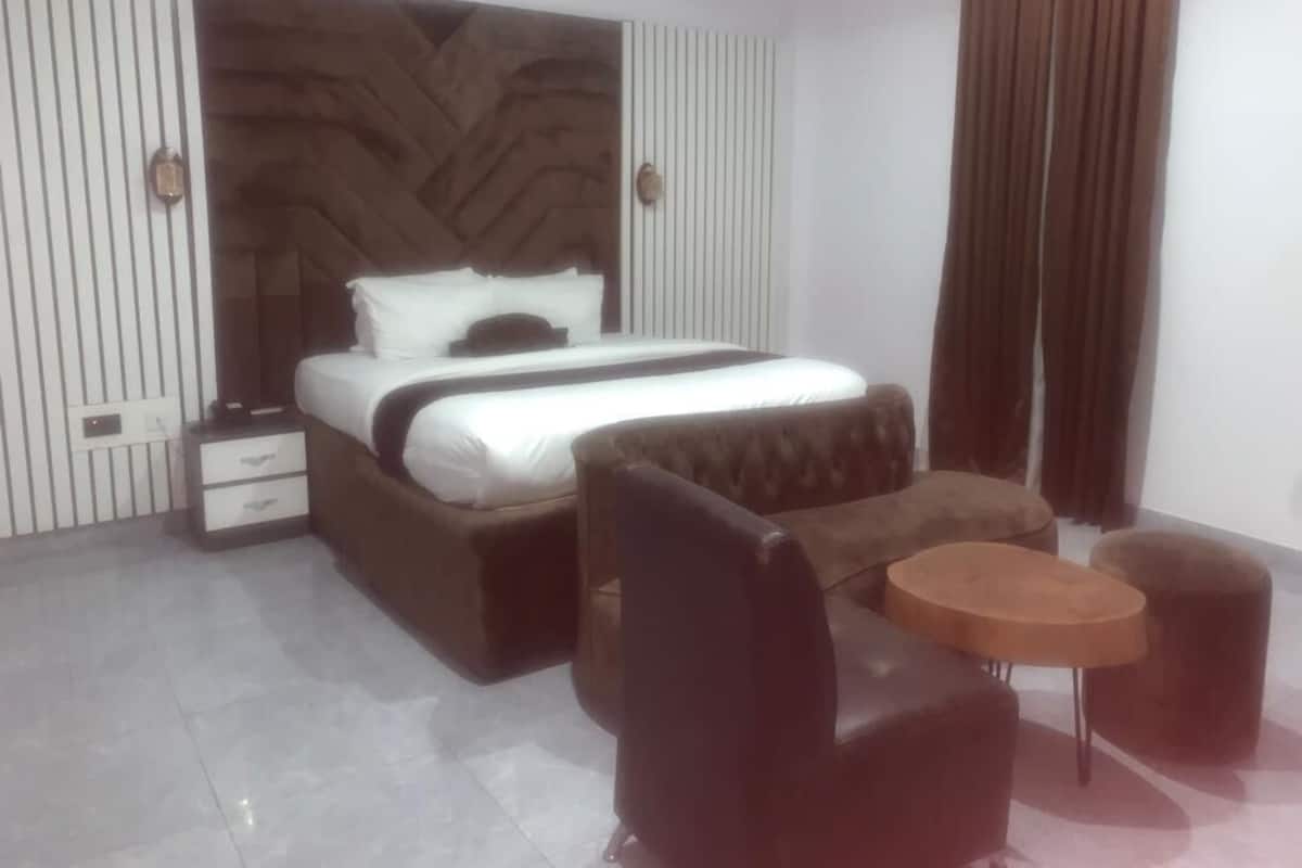 A modern bedroom with a large bed, a nightstand, a sofa, and a small round table.