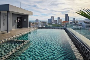 A rooftop pool with a checkered tile pattern, a glass railing, and a cityscape view in the background. - Siam Oriental Star (Pattaya)